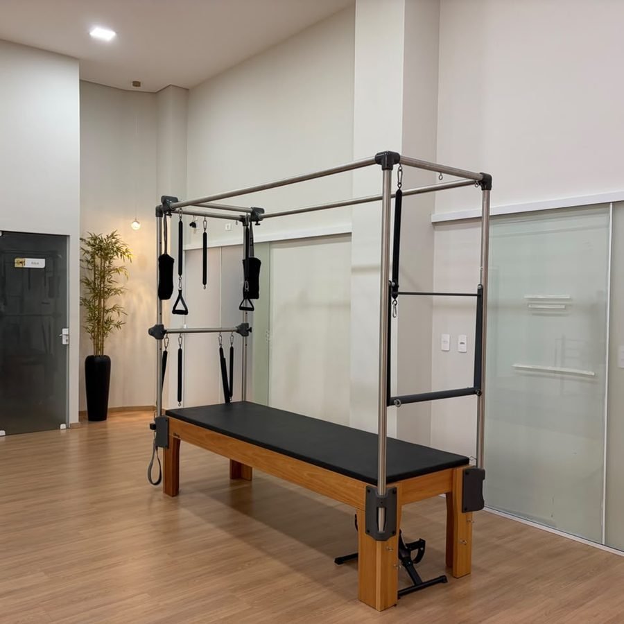 Ambiente da Multiclínica: aparelho de Pilates, piso de madeira e salas com divisórias de vidro