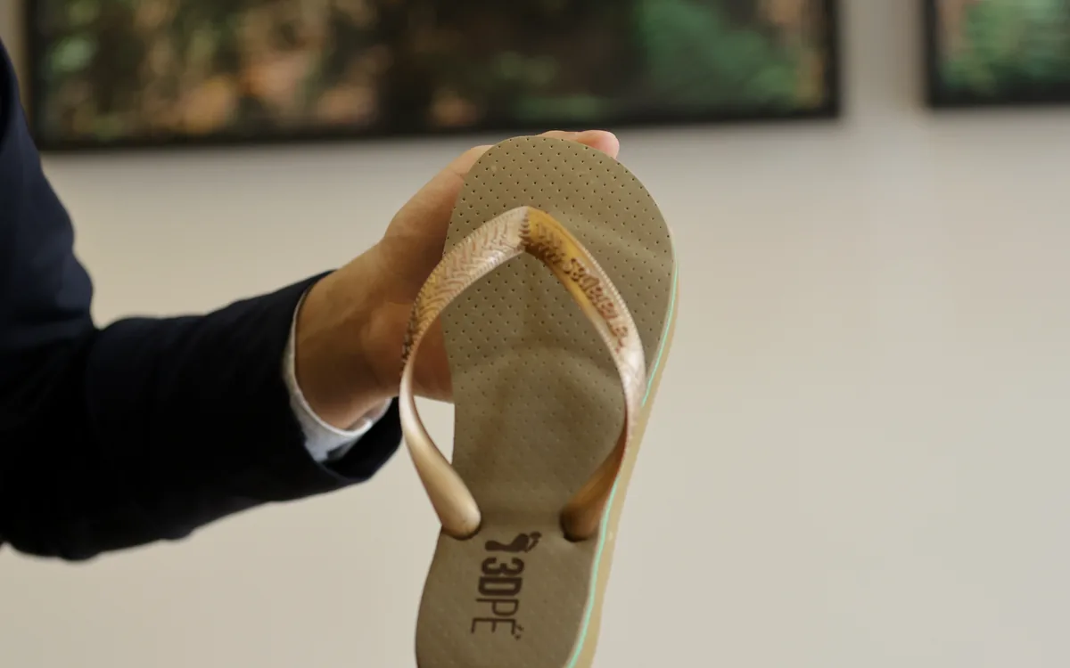 Chinelo com palmilha 3D personalizada visto por baixo, segurado nas mãos